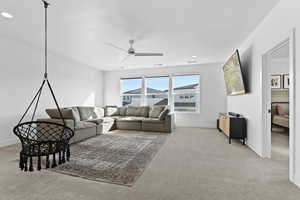 Carpeted living area featuring ceiling fan and recessed lighting