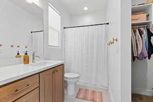 Bathroom with curtained shower, vanity, light tile patterned floors, recessed lighting, and a walk in closet