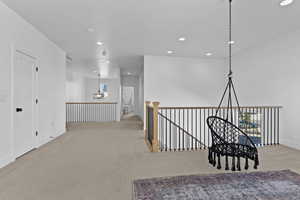 Hallway featuring suspended lighting, carpet floors, and an upstairs landing