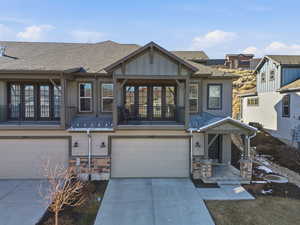 Craftsman inspired home featuring a garage, driveway, stone siding, roof with shingles, and a balcony