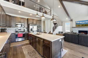 Kitchen with dark wood finish cabinets, stainless steel appliances, dark wood-style flooring, a breakfast bar, and lofted ceiling
