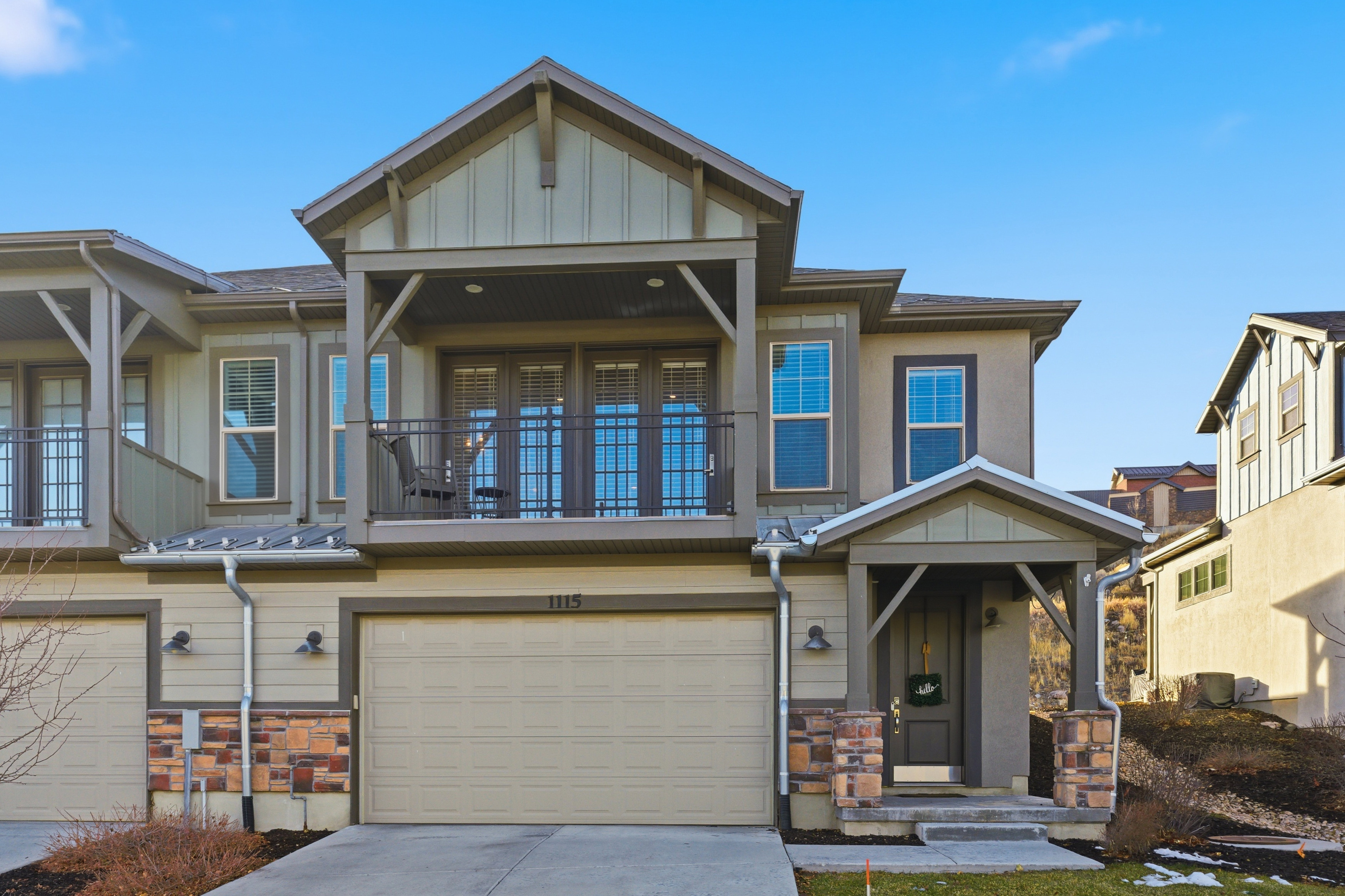Craftsman-style home with stone siding, an attached garage, board and batten siding, and driveway