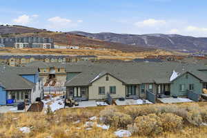 Rear view of property featuring a patio, a mountain view, a shingled roof, and a residential view