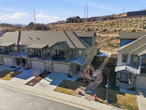 View of front facade with a balcony, driveway, a shingled roof, a garage, and stone siding
