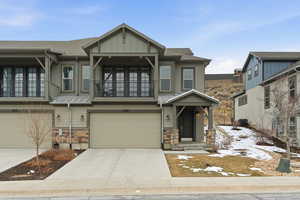 Craftsman-style house with a garage, driveway, stone siding, and a balcony