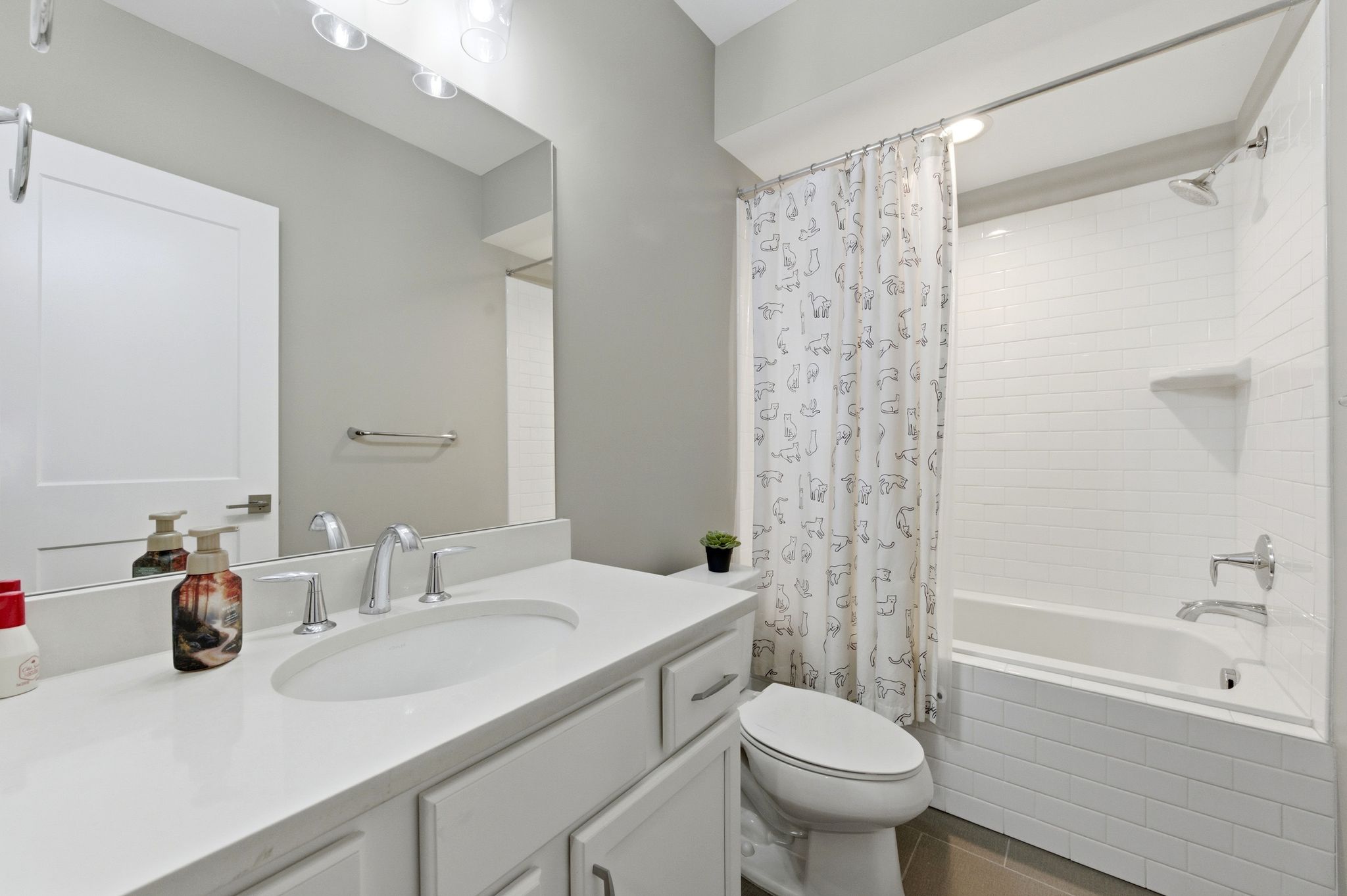 Bathroom with tiled shower / bath, vanity, and dark tile patterned floors