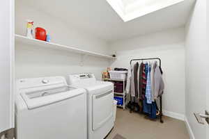 Laundry area featuring a skylight, light tile patterned floors, and separate washer and dryer