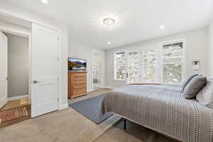 Bedroom with recessed lighting, light colored carpet, and ensuite bath