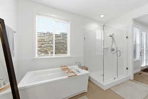Bathroom featuring a freestanding bath, a stall shower, light tile patterned floors, and tile walls