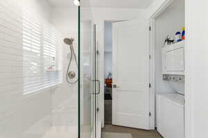 Full bathroom with a stall shower, stacked washer / drying machine, and tile patterned flooring
