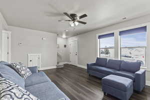 Living area featuring ceiling fan and dark wood-style flooring