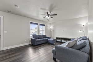 Living room featuring dark wood-type flooring, a ceiling fan
