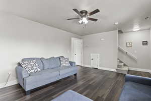 Living room featuring ceiling fan and dark wood-style floors