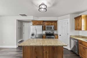 Kitchen featuring a kitchen island, granite countertops, stainless steel appliances, and a pantry