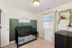 Bedroom featuring a crib and light carpet