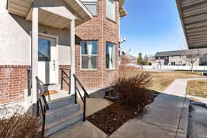 Doorway to property featuring brick siding and stucco siding