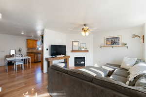 Living area with a glass covered fireplace, light wood finished floors, a ceiling fan, and recessed lighting