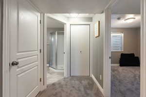 Corridor with light colored carpet and a textured ceiling