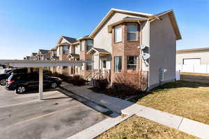 View of front facade with a front lawn, covered parking, and brick siding