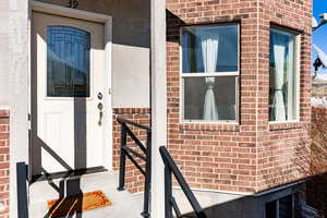 Doorway to property featuring brick siding and stucco siding