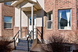 Doorway to property with brick siding and stucco siding