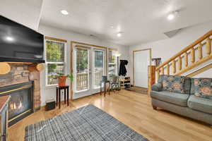 Living room featuring light wood-style floors, a textured ceiling, a stone fireplace, and recessed lighting