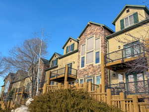 Back of property with stone siding and a balcony