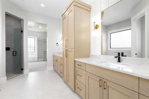 Full bathroom with a spacious closet, two vanities, a shower stall, and recessed lighting