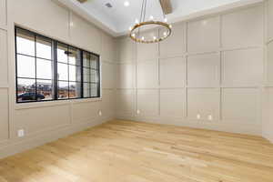 Spare room featuring a decorative wall, a chandelier, and light wood-style floors