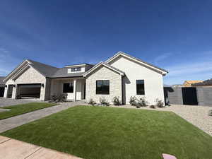 View of front facade with stone siding, an attached garage, covered porch, and stucco siding