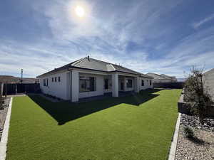 Rear view of house with a fenced backyard, a patio area, and stucco siding