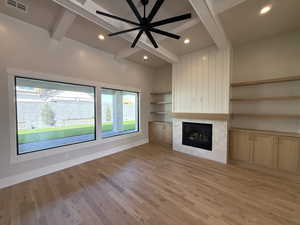 Unfurnished living room with ceiling fan, light wood-type flooring, beam ceiling, a tile fireplace, and recessed lighting