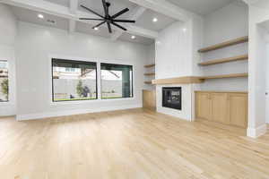 Unfurnished living room featuring a ceiling fan, light wood finished floors, beamed ceiling, a fireplace, and recessed lighting