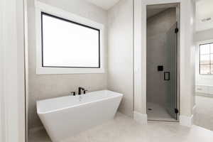 Bathroom featuring a freestanding tub, a shower stall, and light tile patterned flooring