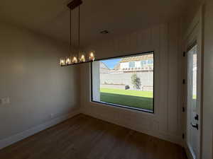 Unfurnished dining area featuring dark wood-type flooring and baseboards