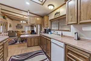 Kitchen featuring white dishwasher, open floor plan, vaulted ceiling, light wood-style floors, and light countertops