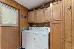 Laundry room with wood walls, cabinet space, and independent washer and dryer