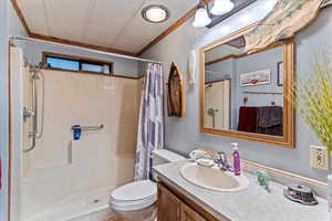 Bathroom with vanity, crown molding, a tile shower, and a textured ceiling