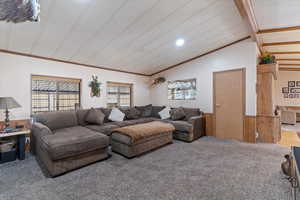 Living room with wooden walls, vaulted ceiling, carpet, and a wainscoted wall