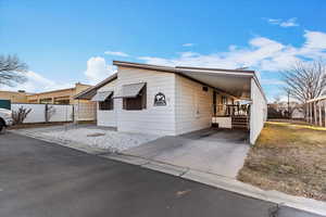 View of front of house with a carport, concrete driveway, and a wooden deck