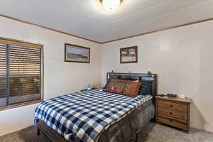 Bedroom featuring carpet, wooden walls, a textured ceiling, and ornamental molding