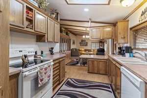 Kitchen featuring white appliances, a peninsula, light wood finished floors, light countertops, and a chandelier