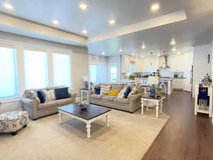 Living area with a raised ceiling, recessed lighting, and dark wood-style floors