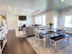 Dining space featuring a glass covered fireplace, recessed lighting, dark wood-style flooring, and a raised ceiling
