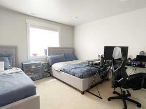 Bedroom featuring light colored carpet and an office area