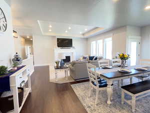 Dining area featuring a fireplace, recessed lighting, dark wood-type flooring, and a raised ceiling