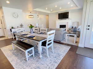 Dining space featuring a fireplace, a raised ceiling, dark wood finished floors, and hanging lights