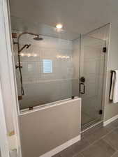 Bathroom featuring a shower stall, dark tile patterned floors, and a textured ceiling