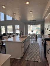Kitchen with stainless steel appliances, hanging light fixtures, open floor plan, a center island with sink, and dark wood-style floors