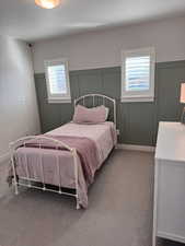 Carpeted bedroom featuring a decorative wall, wainscoting, and a textured ceiling